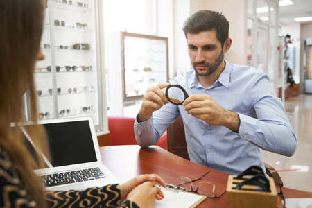 Troubled man studying loupe with grainy material inside it
