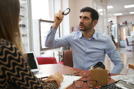 Curious man lifting loupe with grains to light