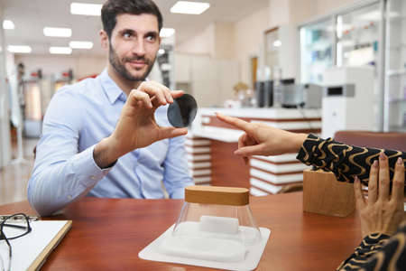 Male holding sunglasses lens in hand over tableの写真素材