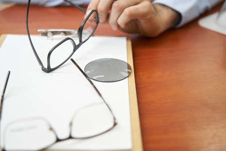 Optical lens on table near pair of glassesの写真素材