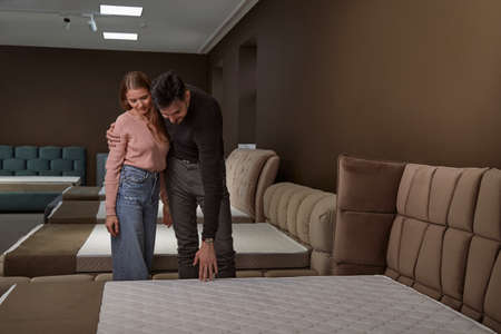 Couple standing among beds in furniture storeの写真素材