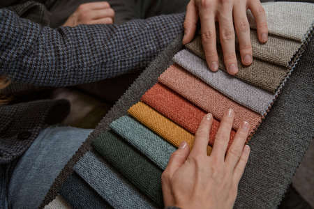 Two shoppers selecting right sofa upholstery fabricの写真素材