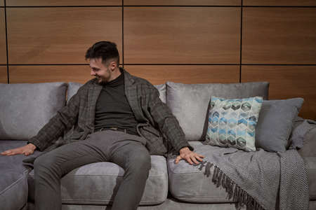 Cheerful stylish male shopper choosing new sofaの写真素材
