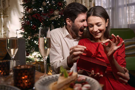 Happy couple holding a gift on christmas eveの写真素材