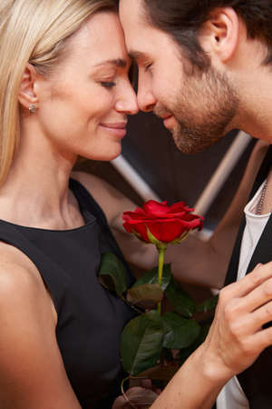 Lovely couple holding rose between them while dancing