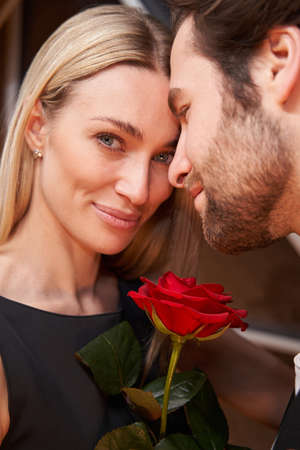 Female with rose looking at camera near her partnerの写真素材