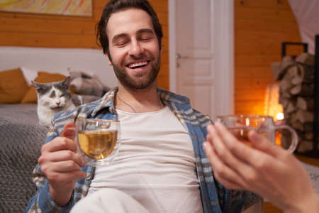 Joyful man having tea in bedroom near catの写真素材
