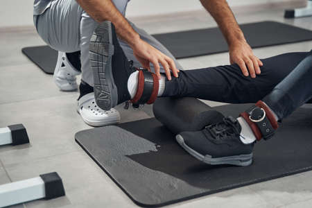Patient foam-rolling lower leg muscles assisted by physiatrist