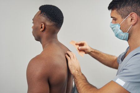 Doctor treating upper back pain using medical taping techniqueの写真素材