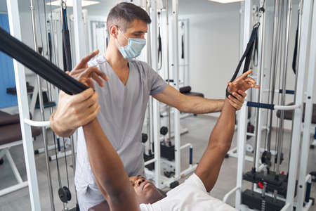Rehabilitation physician working with patient at gym