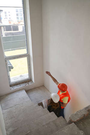 Construction worker showing staircase window to engineer