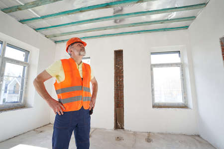 Professional male builder is examining room ceiling