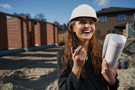 Laughing woman worker with layout talking by radioの写真素材