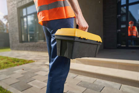 Worker bringing kit with instruments to house porchの写真素材