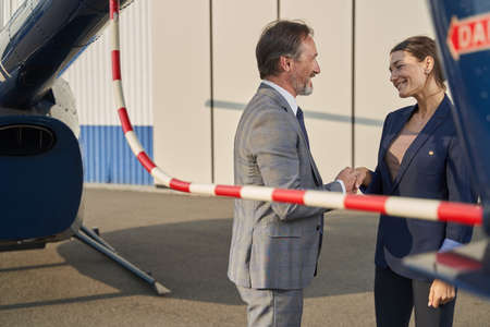 Smiling businessman and pleased businesswoman greeting each other outdoorsの写真素材