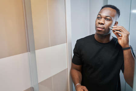 Male using electric shaver on his face before mirror