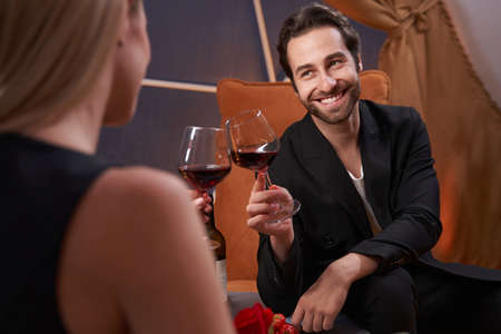 Happy man clinking glasses of wine with his girlfriend