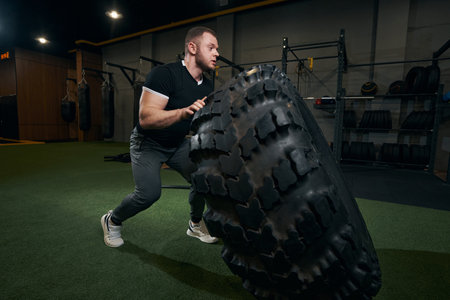 Concentrated sportsman performing tyre exercise at gymの写真素材