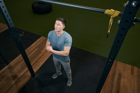 Concentrated sporty male getting ready for pull-ups
