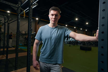 Tranquil athletic young male standing at gym
