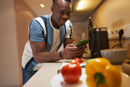 Male with smartphone leaning on kitchen tableの写真素材