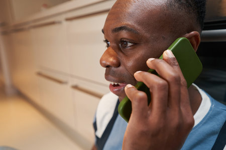 Multiracial man in kitchen speaking on phone