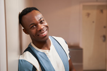 Happy multiracial man smiling to camera near wallの写真素材