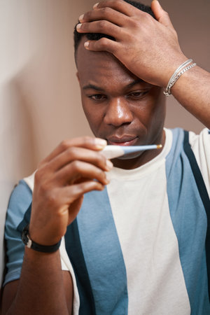 Shocked man staring at his temperature values on thermometer