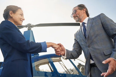 Cheerful woman and man greeting each other near helicopter