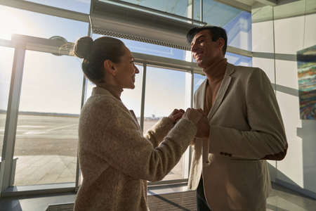Happy man keeping woman hands inside airportの写真素材