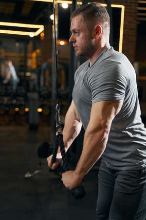 Sportsman working out on cable machine at gym