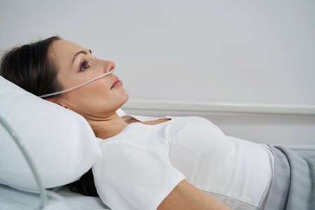 Ill young female patient undergoing oxygen therapyの写真素材