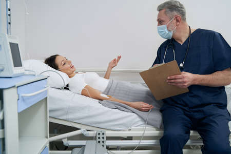 Joyous female patient communicating with doctor during intravenous therapy