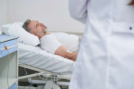 Recumbent patient staring at attending doctor during ward roundの写真素材