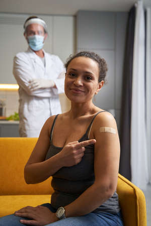 Pleased lady showing medical plaster on her shoulder