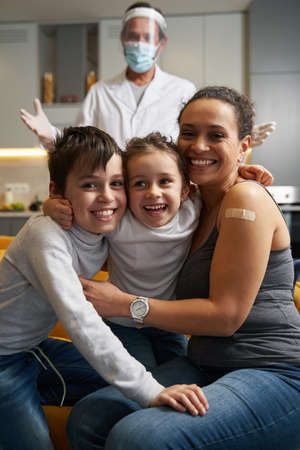 Happy family smiling to camera with doctor behind themの写真素材