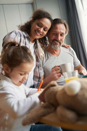 Man with his wife drinking tea and looking at daughter
