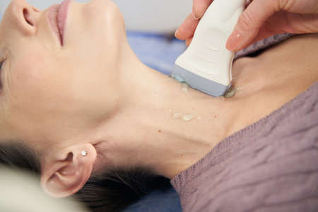 Sonographer examining patient thyroid gland with ultrasoundの写真素材