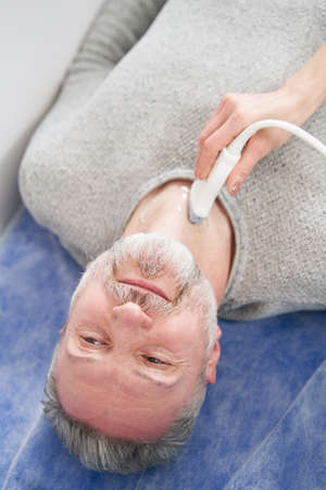 Calm mature male patient undergoing ultrasonography procedureの写真素材