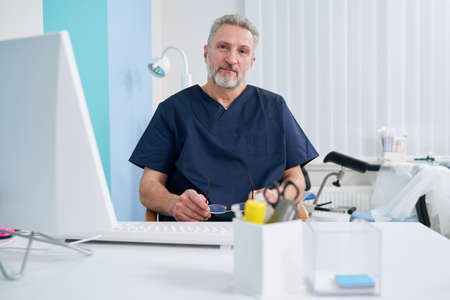 Calm male physician sitting at desktop computerの写真素材
