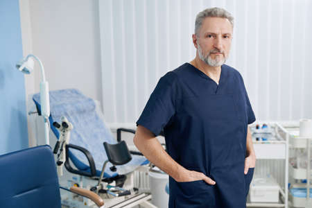 Serious male gynecologist standing in his office