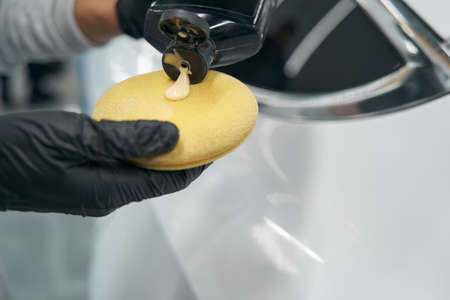 Gloved hands applying liquid wax on foam spongeの写真素材