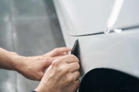 Worker hands polishing exterior surface of auto body panelの写真素材