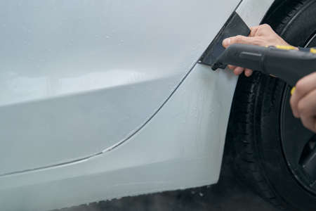 Service station worker washing customer car with cleaning toolsの写真素材