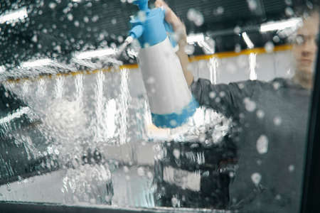 Worker misting vehicle exterior surfaces with cleaning solutionの写真素材