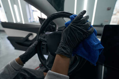 Worker in nitrile gloves cleaning interior of customer car