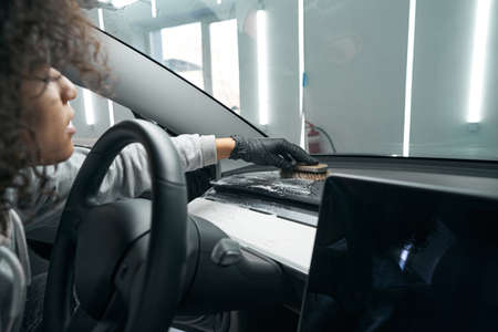 Skilled worker cleaning dashboard cover in passenger vehicle