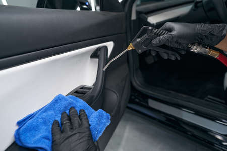 Service station worker using pneumatic tool on automotive interior surface