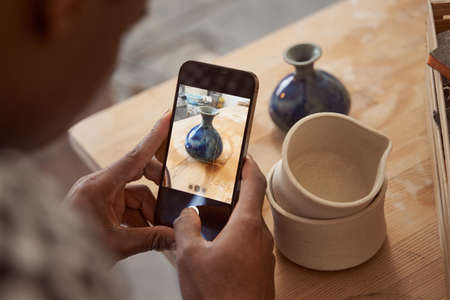 Male ceramist taking picture of pottery productの写真素材