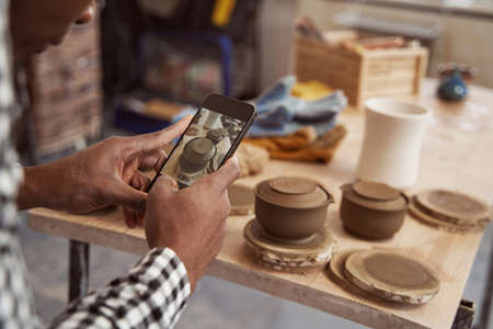 Ceramic artist photographing clay pots on tableの写真素材